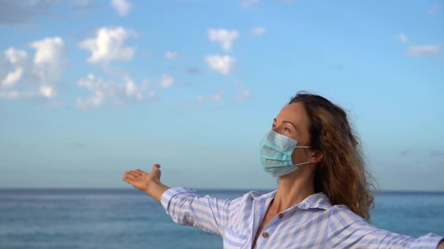 Happy woman wearing medical mask outdoor against blue sky background