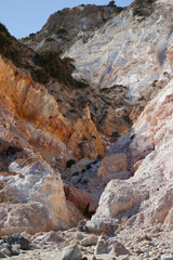 Fototapeta na wymiar cliff of red and orange sulfur rocks on the wild Greek island of milos