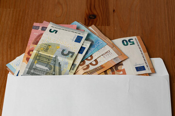 Closeup with envelope full of Euro banknotes on wooden background