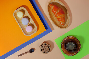 Coffee in a cup in a composition with dessert, on a bright, colorful background.