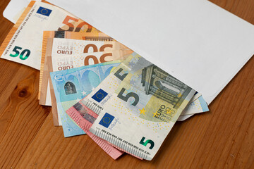 Closeup with envelope full of Euro banknotes on wooden background