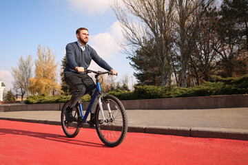 Happy handsome man riding bicycle on lane in city