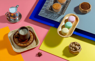 Coffee in a cup in a composition with pastries and dessert, on a bright colored background.