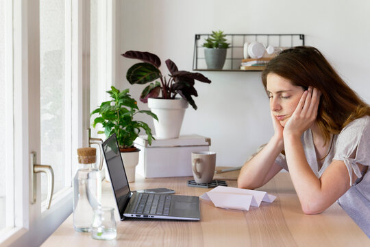 Tired woman with head resting in arms at home office