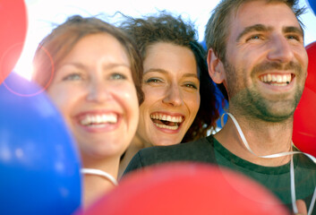 Happy male and female friends amidst red and blue balloons