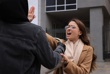 Woman fighting with thief while he trying to steal her bag on city street. Self defense concept
