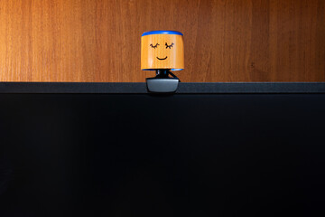 External round black web camera with a smiling cap on a black monitor. Smiling cover for a webcam. Protection against spying.