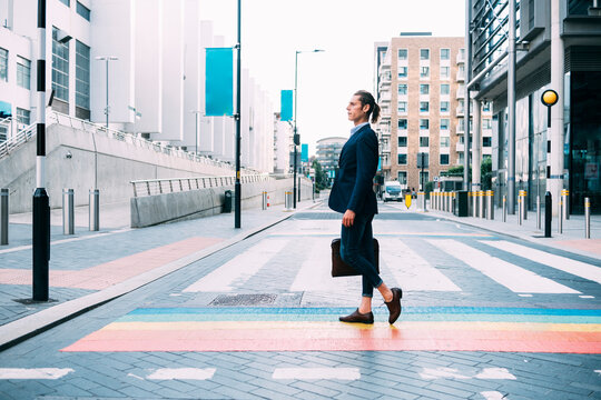 Businessman holding briefcase while walking on multi colored road markings in city