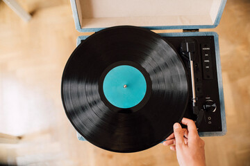 Musician holding record on turntable at home