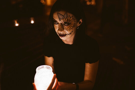 Woman holding illuminated jar with friend at night during Halloween