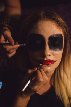 Friends doing make-up of woman during Halloween