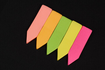 Set of multicolored slim paper office indexes with adhesive on black background.