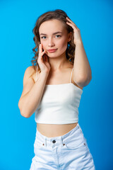 Naklejka premium studio, beautiful woman. model on a blue background in white shorts and a t-shirt. model pose. PHOTOSESSION. side lighting. silhouette