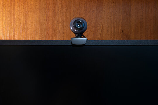 External Round Black Web Camera On A Black Monitor. Webcam On A Wooden Background.