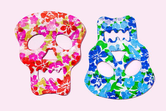 Studio shot of two red and blue skull masks decorated with floral patterns
