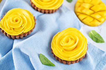 Chocolate tartlets with chocolate cream filling and mango fruit in the form of roses