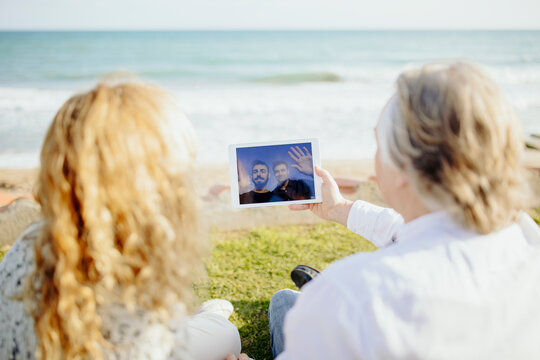 Mature couple doing doing video call to grandsons through digital tablet during vacation
