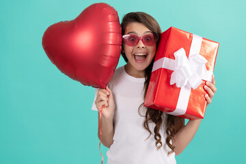 fashionable teen girl in sunglasses hold giftbox and heart balloon. love gift. surprised kid