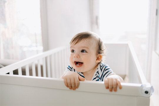 Cute baby boy looking away in crib at home