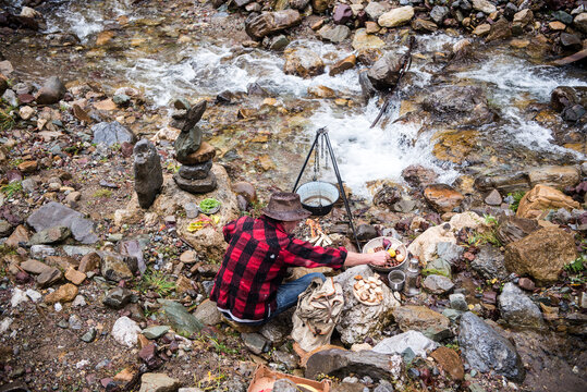 Senior man camping alone on stream bank