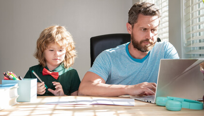 serious father and child son at school working online on laptop, homeschooling