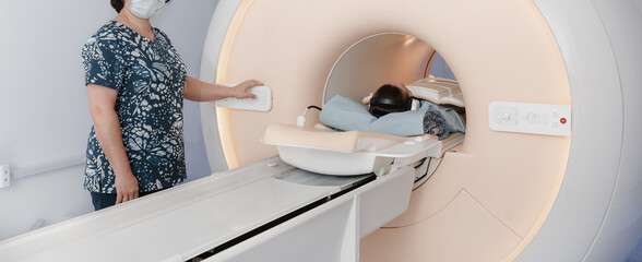 Doctor or nurse and patient with tomography CT or MRI Scan in hospital. Interior of radiography...