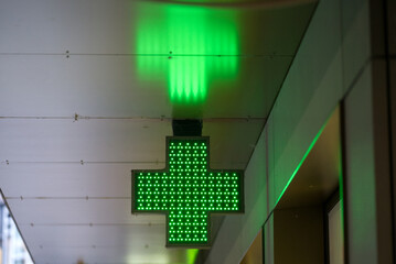 Illuminated green pharmacy cross sign with reflections at City of Zürich on a rainy winter day....
