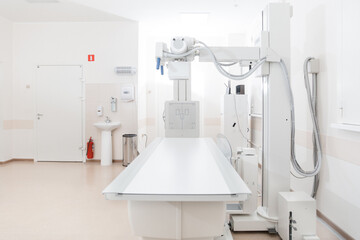 X-ray department in modern hospital. Radiology room with scan machine with empty bed. Technician adjusting an x-ray machine. Scanning chest, heart, lungs in modern clinic office