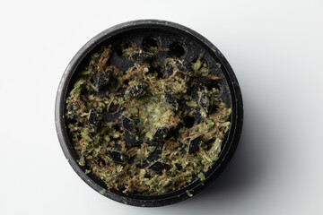 Grinder with Crushed buds of marijuana weed cannabis isolated, medical marijuana