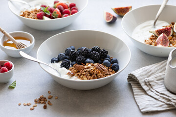 Granola with yogurt, blueberries and blackberries on a concrete background
