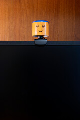 External round black web camera with a smiling cap on a black monitor. Smiling cover for a webcam. Protection against spying.
