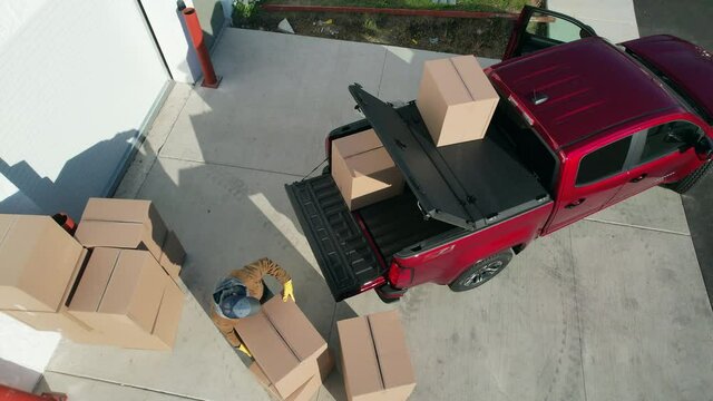 Caucasian Contractor Worker and His Red Modern Pickup Truck. Delivery Products Inside Cartoon Boxes. Aerial View. 
