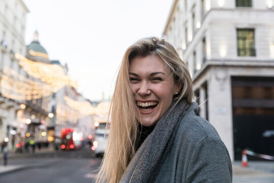 Young blond woman with blond hair laughing while standing in city