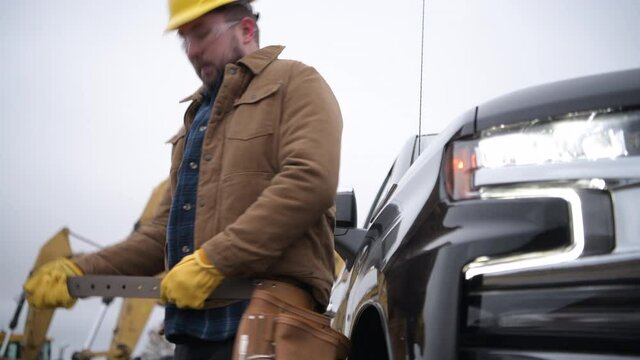 Caucasian Construction Contractor Worker Wearing His Tools Belt Next to His Pickup Truck.
