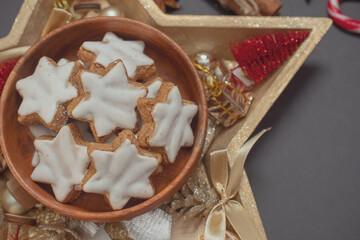 Star-shaped Christmas cookies with white icing on a black New Year's Eve background with Christmas tree branches 
