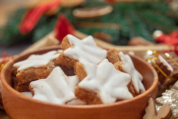 Star-shaped Christmas cookies with white icing on a black New Year's Eve background with Christmas tree branches 