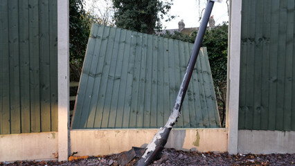 Broken fence panel with bent lamp post in the foreground