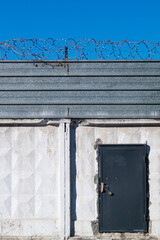 A black abandoned metal door in the white concrete wall
