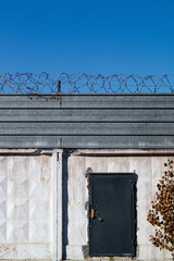 A black abandoned metal door in the white concrete wall