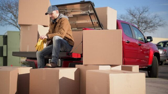 Caucasian Courier in His 40s with Shipping Boxes Parcels Taking Short Break Seating on His Pickup Truck. Unloading Cargo.
