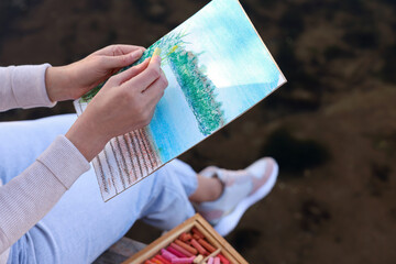 Fototapeta na wymiar Woman drawing with soft pastels near river, closeup
