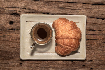 Breakfast food croissant in plate and coffee on wood table.