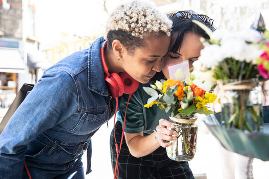 Lesbian Couple Smelling Flowers At Street Market