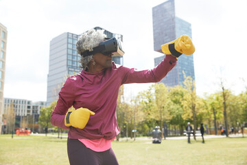 Active woman boxing with virtual reality headset at park