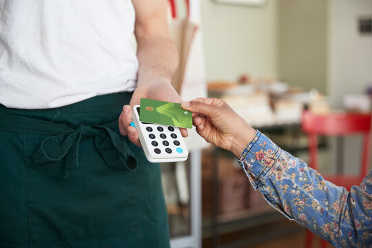 Woman using credit card for making contactless payment at cafe