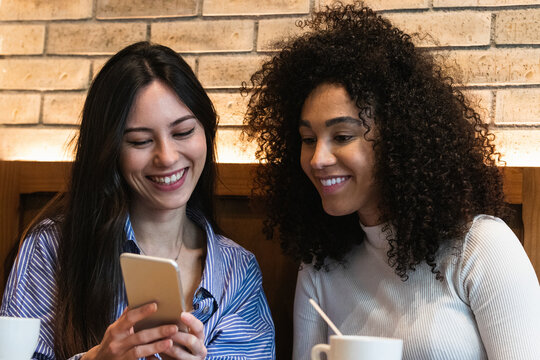Smiling female friends using smart phone at bar
