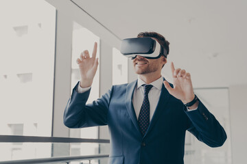 Excited office worker in vr headset or virtual reality goggles gesturing with hands
