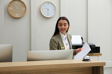 Beautiful receptionist working at counter in hotel - obrazy, fototapety, plakaty