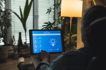 Woman accessing home automation through laptop at home