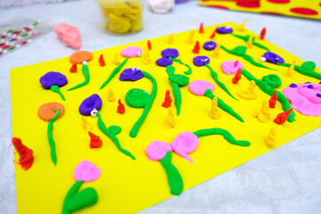 Little girl making  flowers from plasticine, beads,  blooming meadow from paper and clay, card as gift for Mothers day or Birthday . Arts  summer crafts concept. Shallow DOF